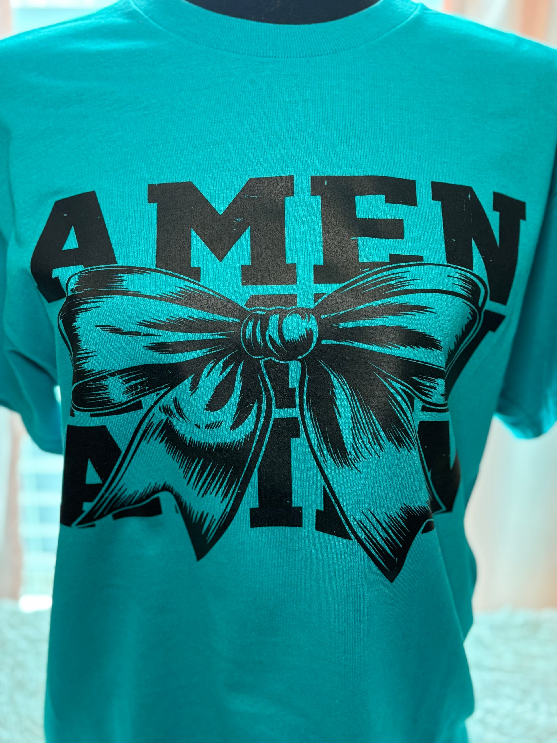 Teal heat press t-shirt with a black bow graphic and 'AMEN' text