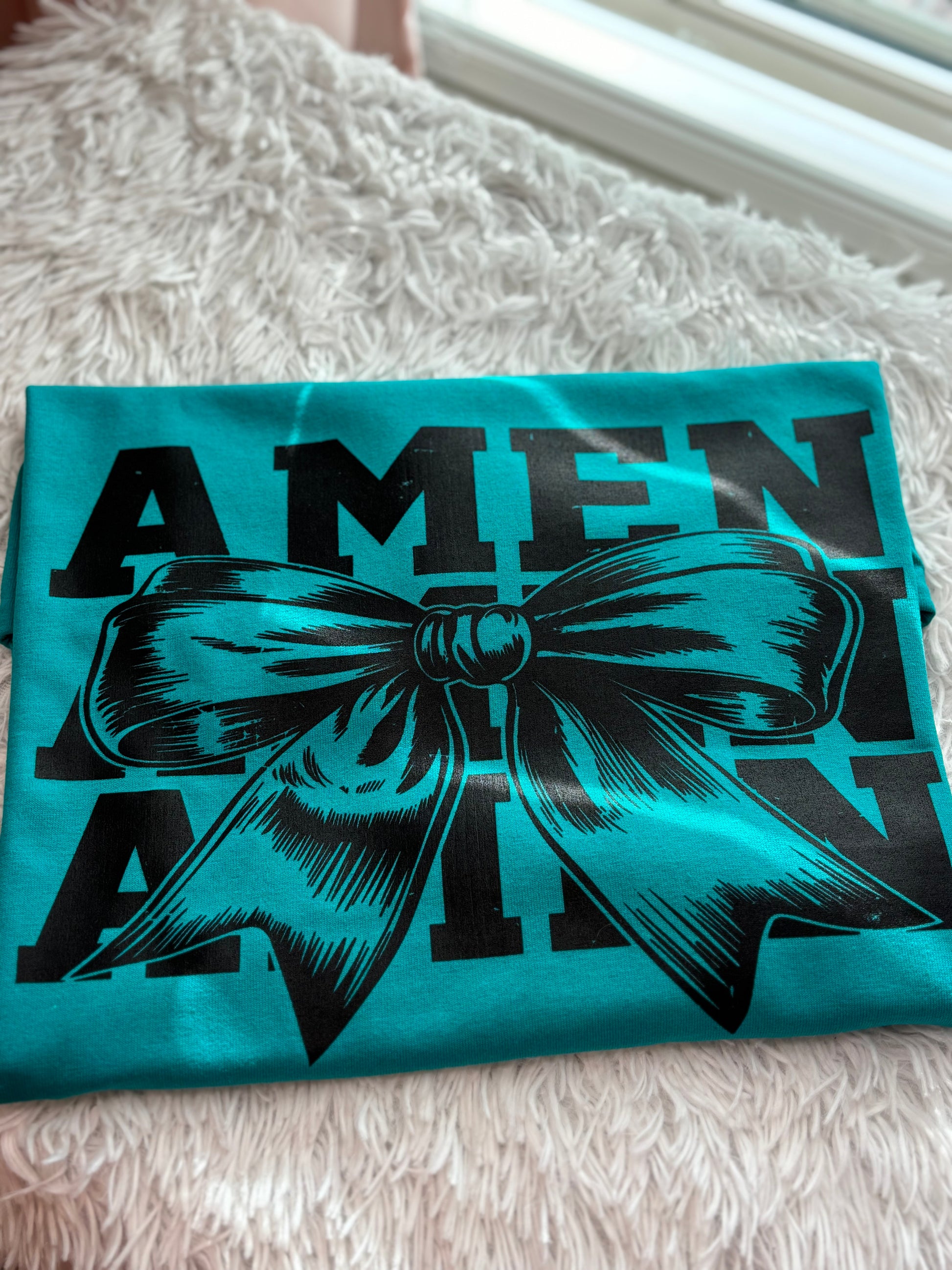 Teal heat press t-shirt with a black bow graphic and 'AMEN' text