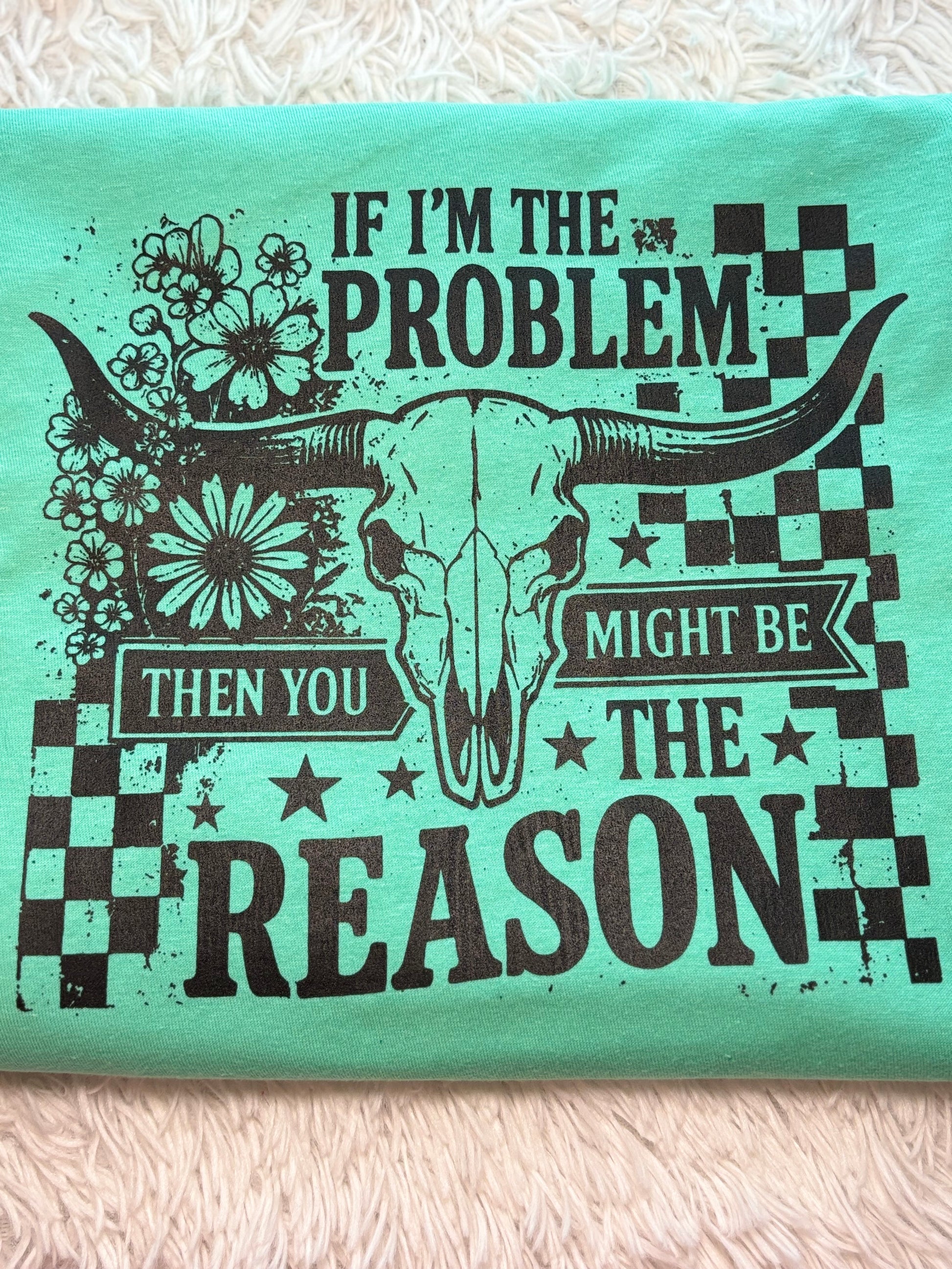 Mint heat press t-shirt with bull skull design and text "If I'm The Problem Then You Might Be The Reason" on a checkered background
