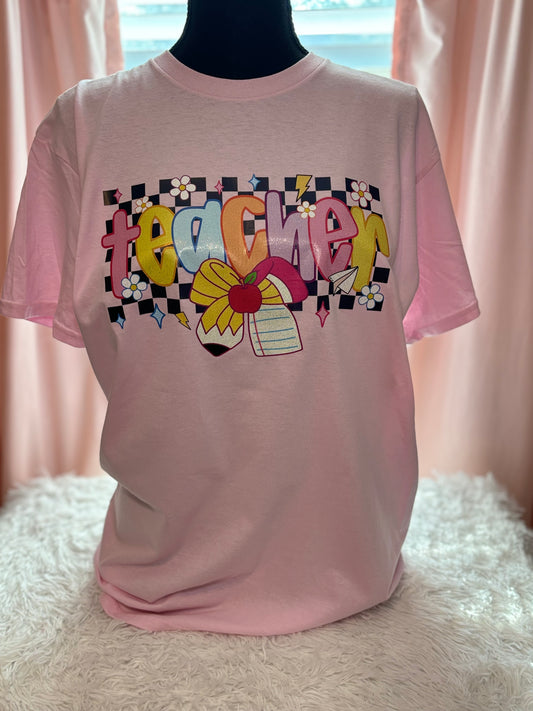 Pink heat press t-shirt with colorful 'teacher' design with checker background and pencil / paper bow