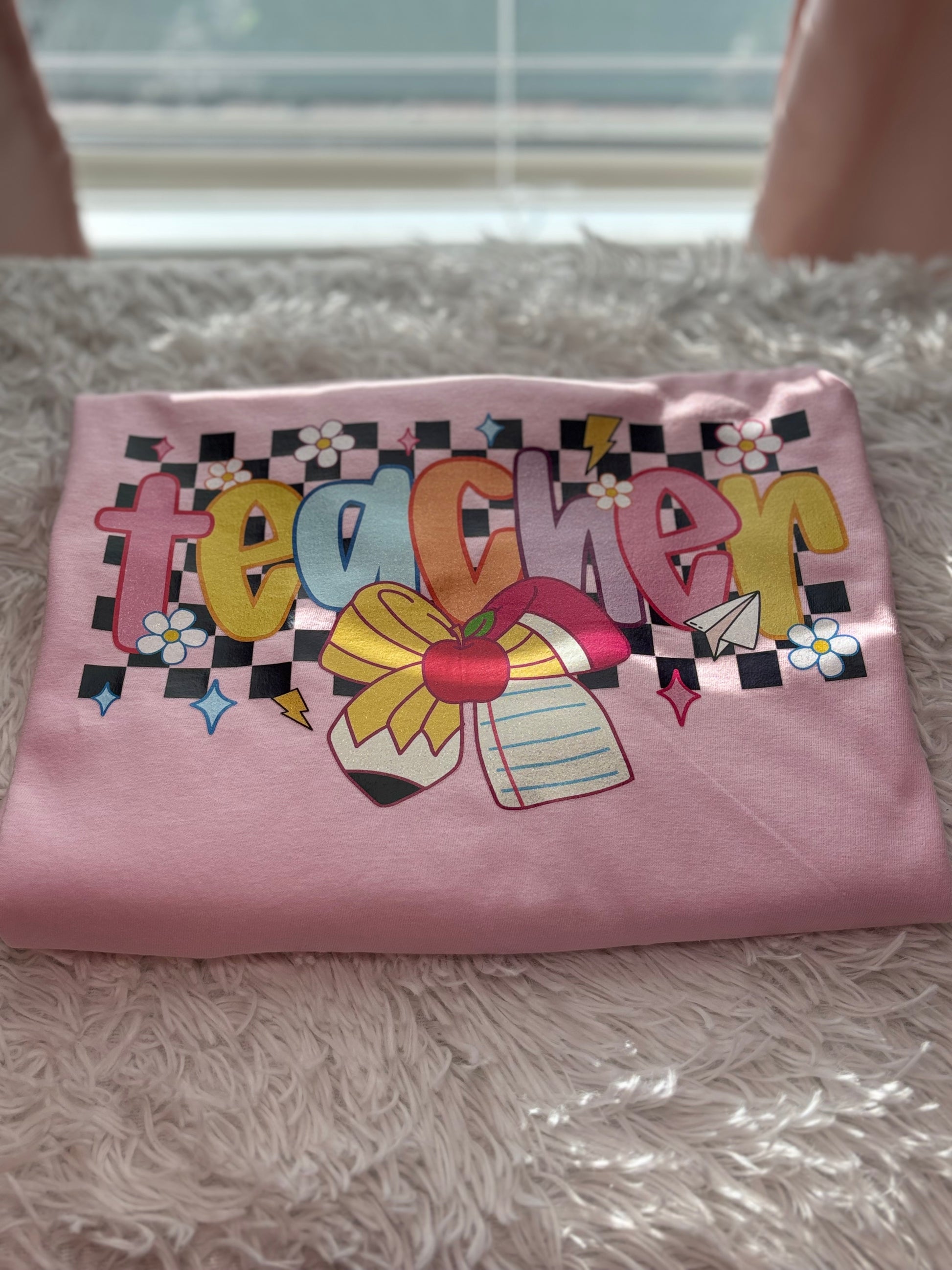 Pink heat press t-shirt with colorful 'teacher' design with checker background and pencil / paper bow