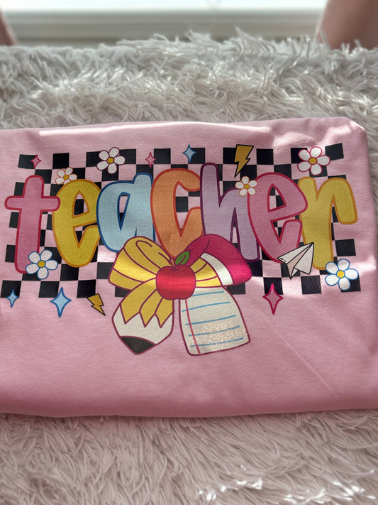 Pink heat press t-shirt with colorful 'teacher' design with checker background and pencil / paper bow