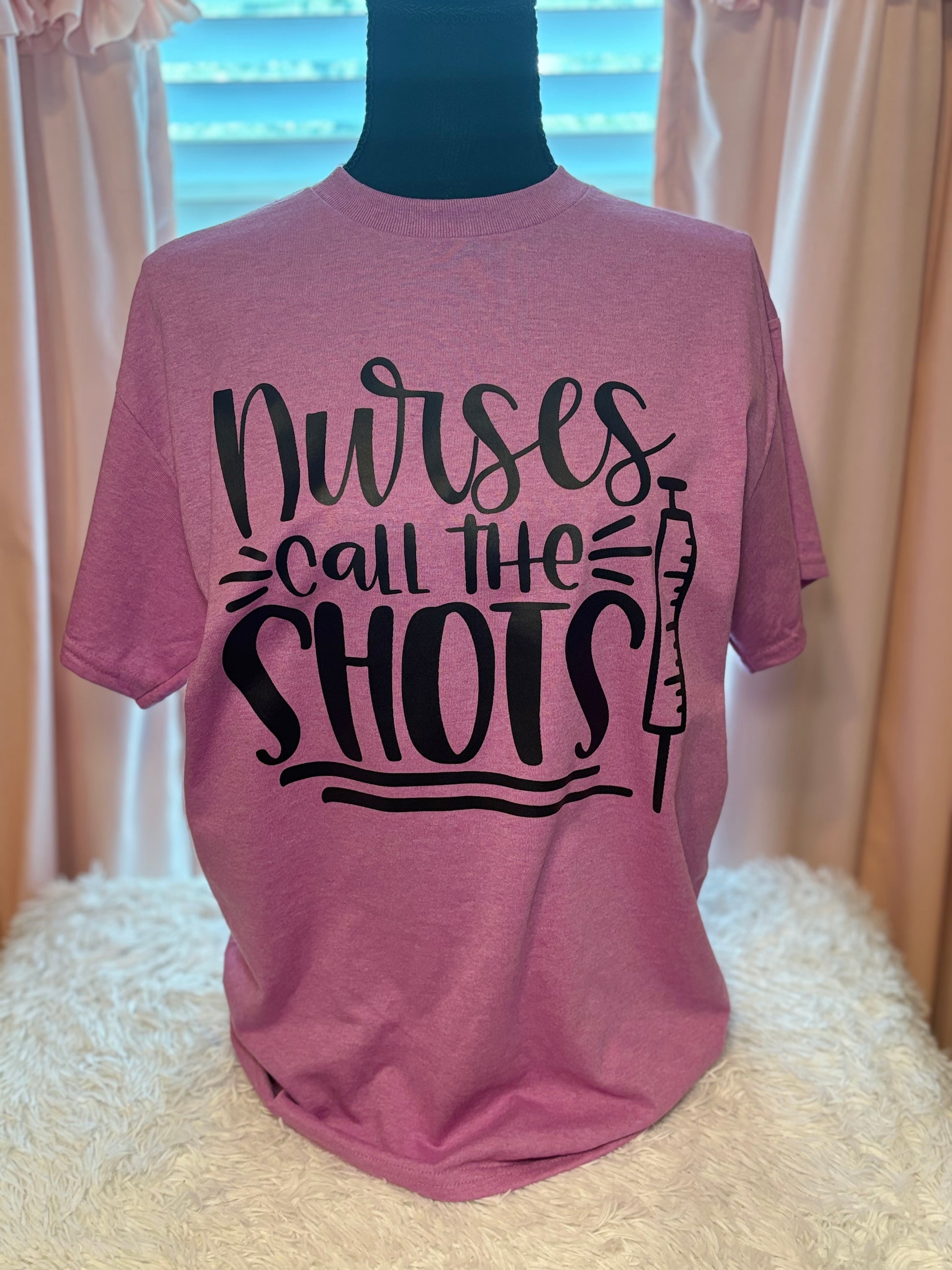 Pink heat press t-shirt with 'Nurses call the shots' text and a syringe black graphic
