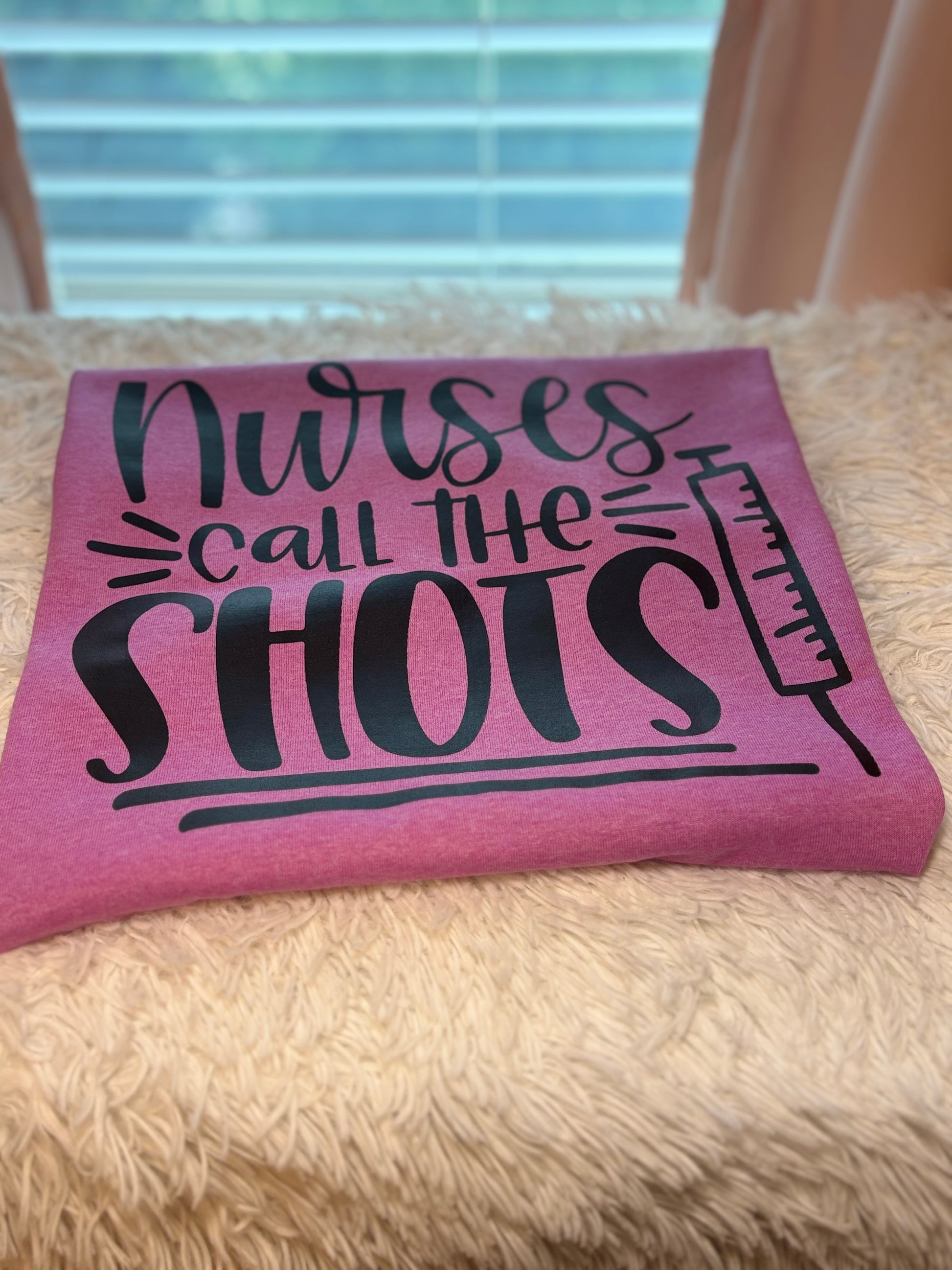 Pink heat press t-shirt with 'Nurses call the shots' text and a syringe black graphic