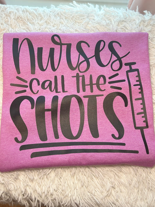 Pink heat press t-shirt with 'Nurses call the shots' text and a syringe black graphic