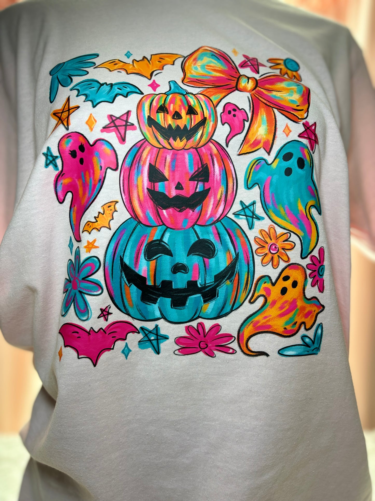 Colorful Halloween-themed heat press design on a pink shirt with pumpkins, ghosts, and bows.