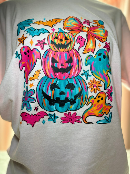 Colorful Halloween-themed heat press design on a pink shirt with pumpkins, ghosts, and bows.