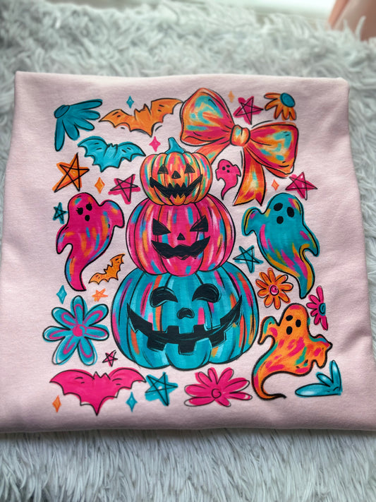 Colorful Halloween-themed heat press design on a pink shirt with pumpkins, ghosts, and bows.