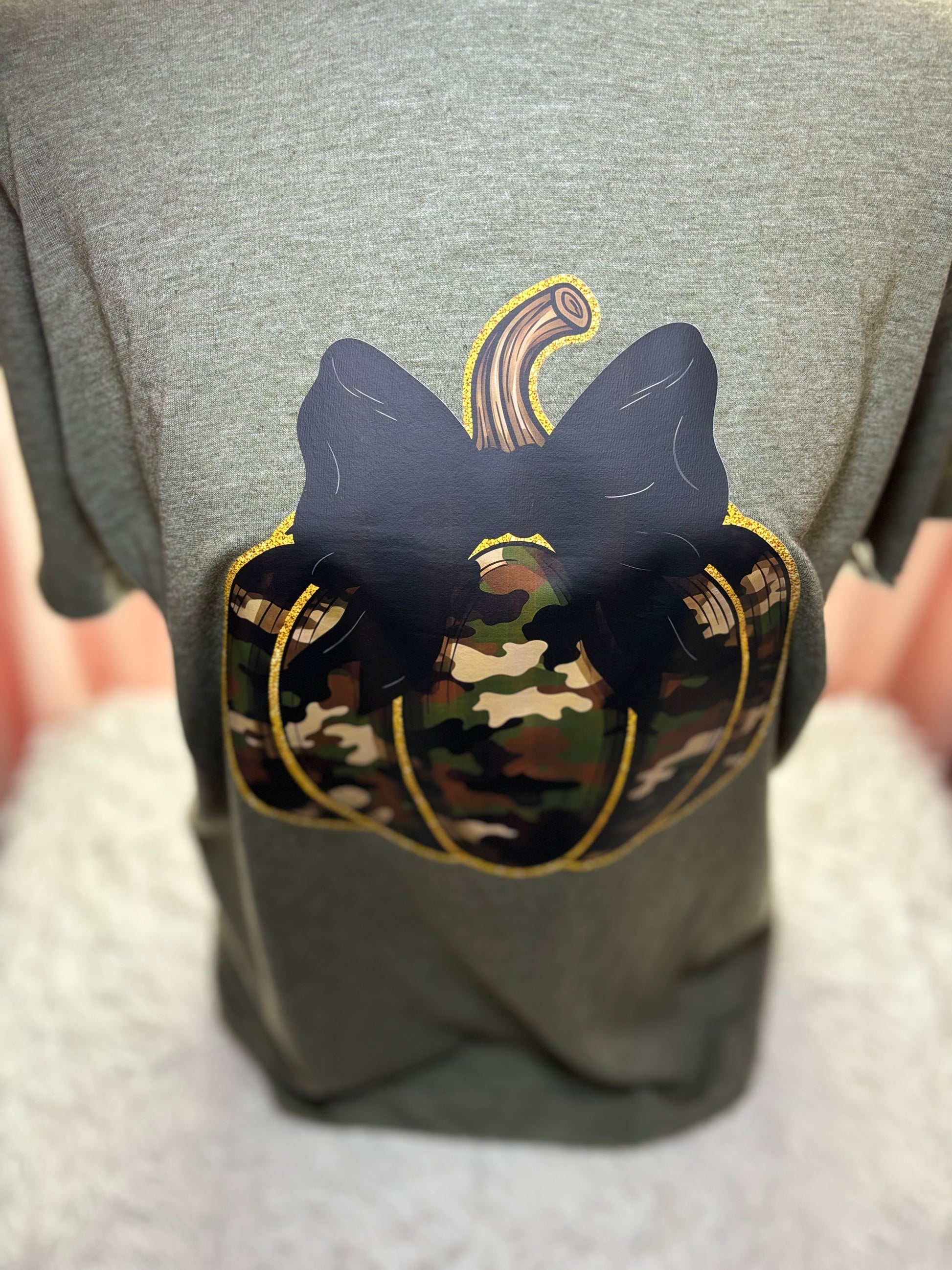 Military green t-shirt with a heat press camouflage pumpkin with bow and outlined in gold