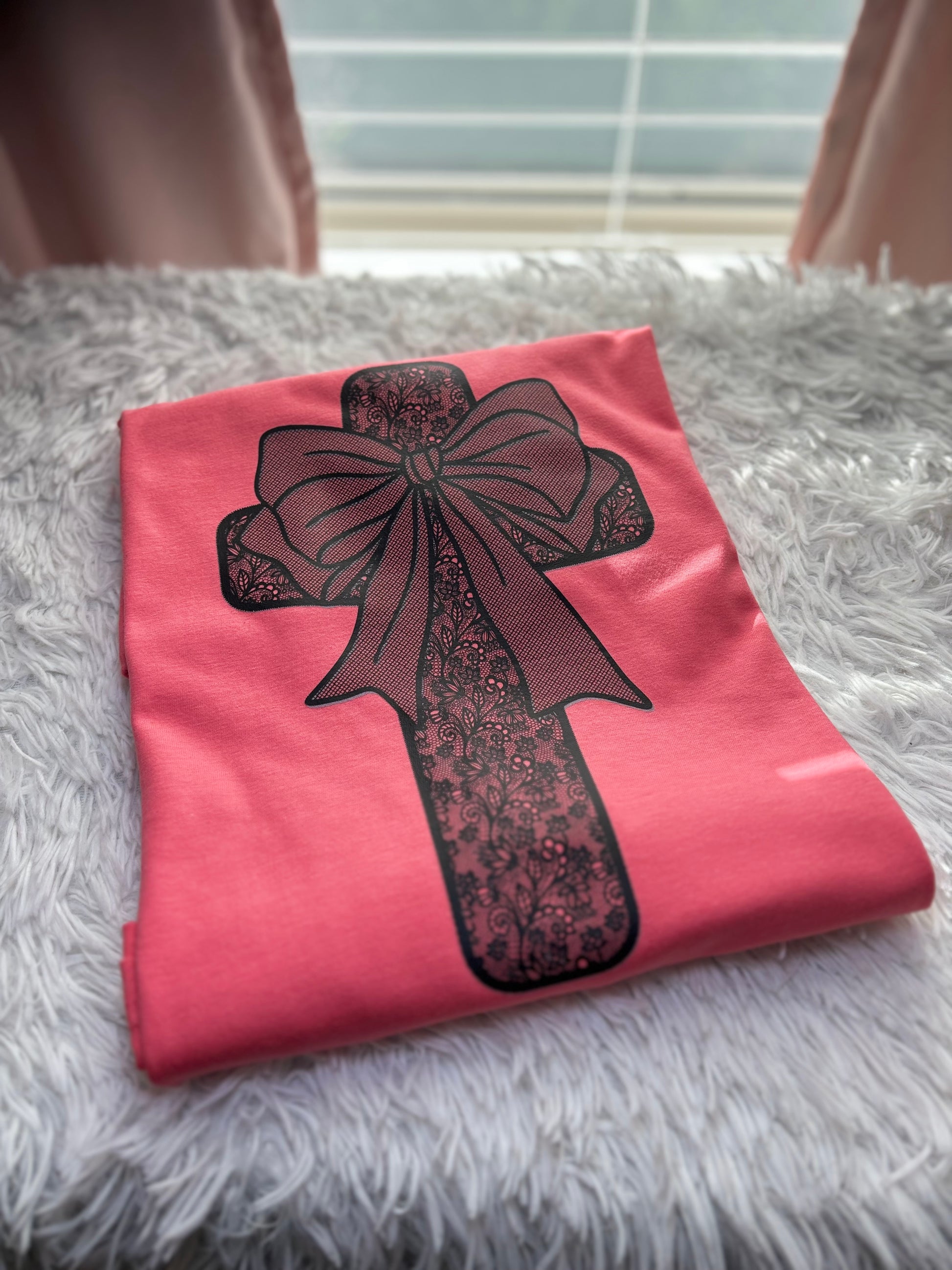 Coral heat press t-shirt with a black lace cross and bow design