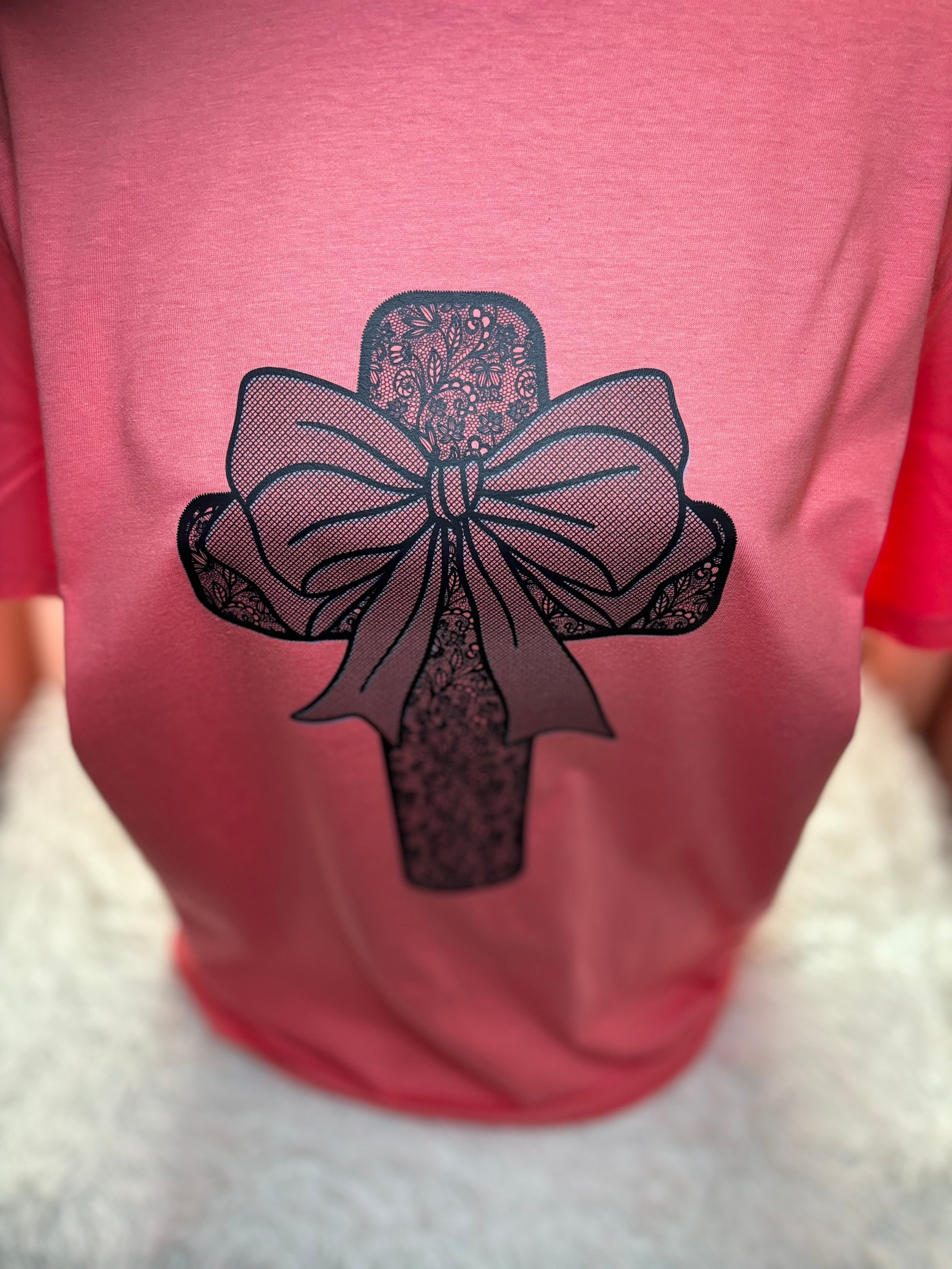 Coral heat press t-shirt with a black lace cross and bow design