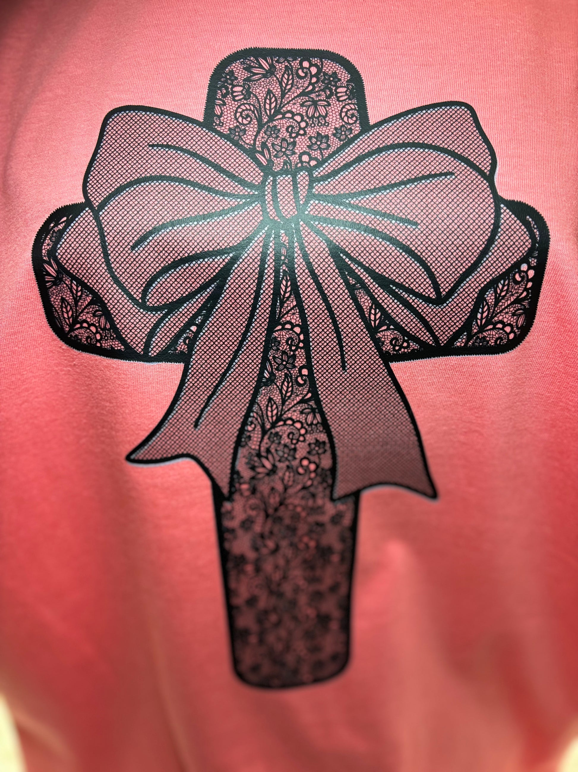 Coral heat press t-shirt with a black lace cross and bow design