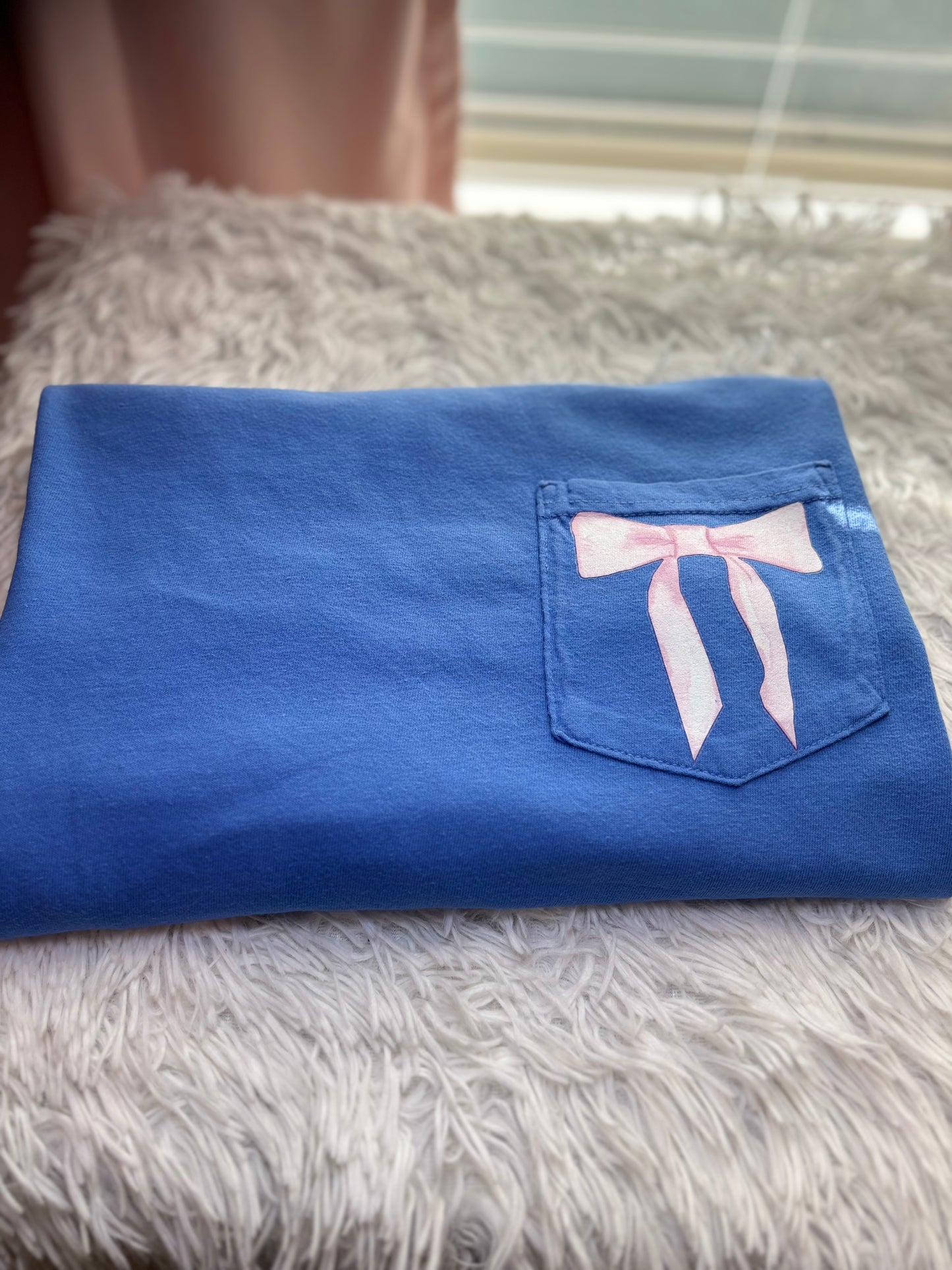 Blue heat press pocket t-shirt with colorful bows and 'She is strong' text on the back and bow on the front pocket