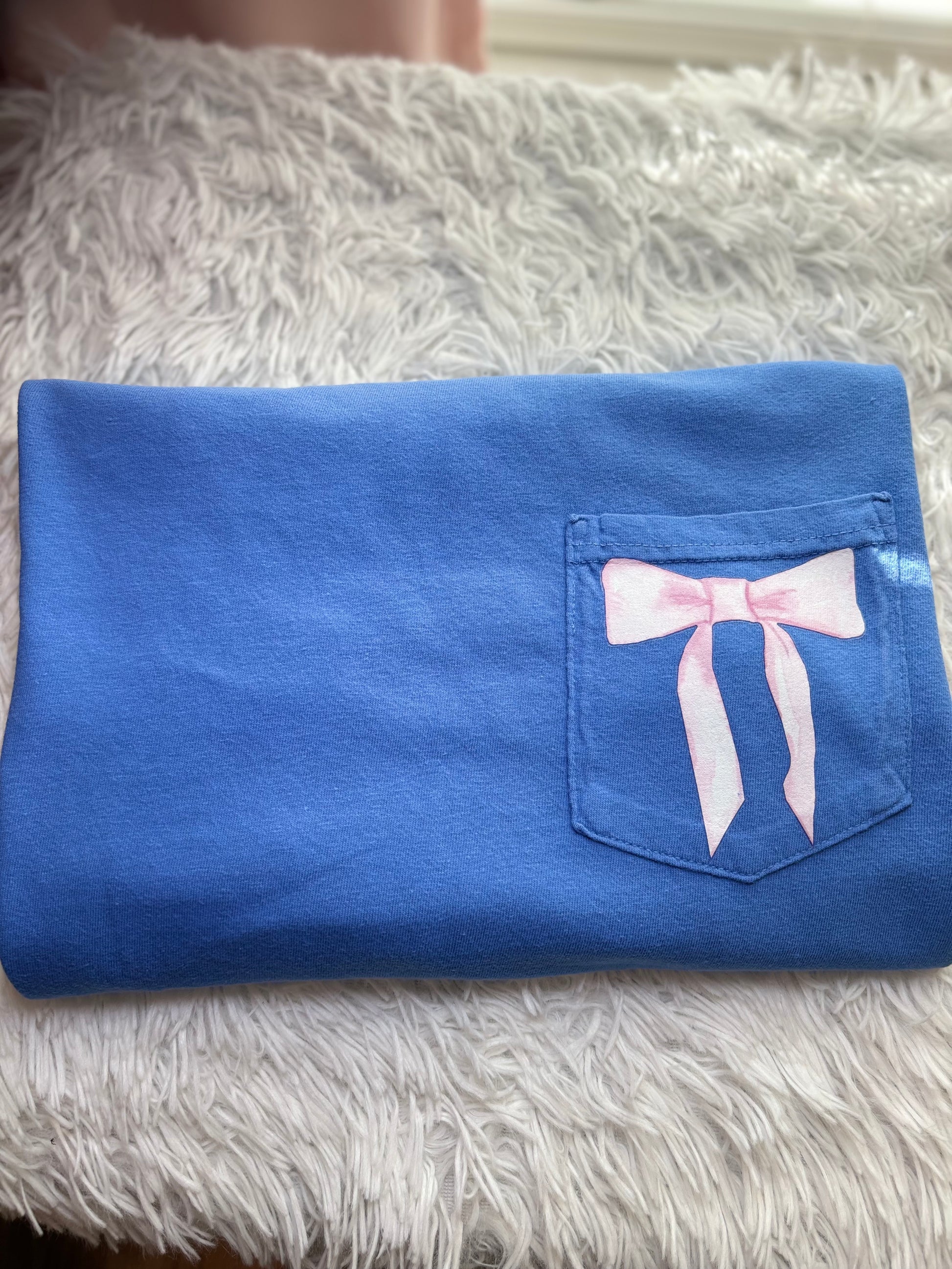 Blue heat press pocket t-shirt with colorful bows and 'She is strong' text on the back and bow on the front pocket
