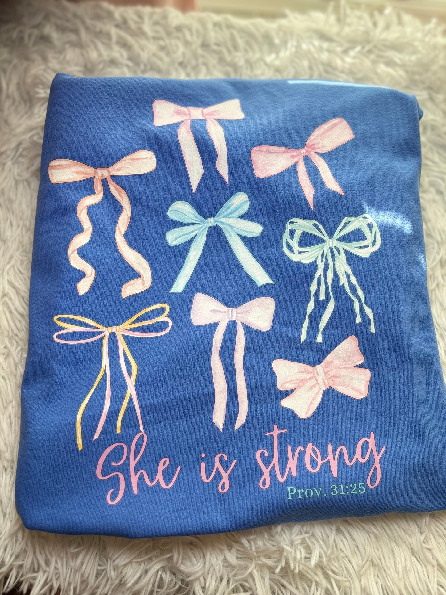 Blue heat press pocket t-shirt with colorful bows and 'She is strong' text on the back and bow on the front pocket