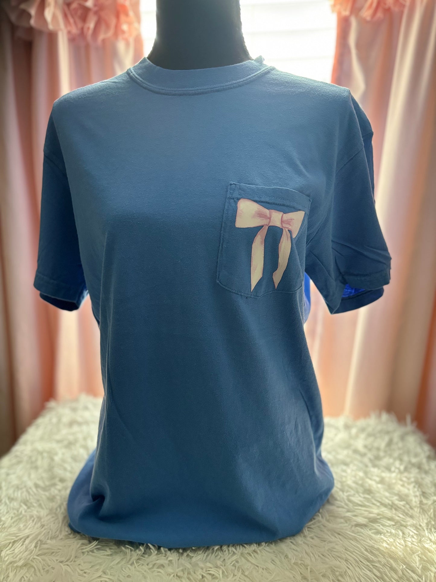 Blue heat press pocket t-shirt with colorful bows and 'She is strong' text on the back and bow on the front pocket