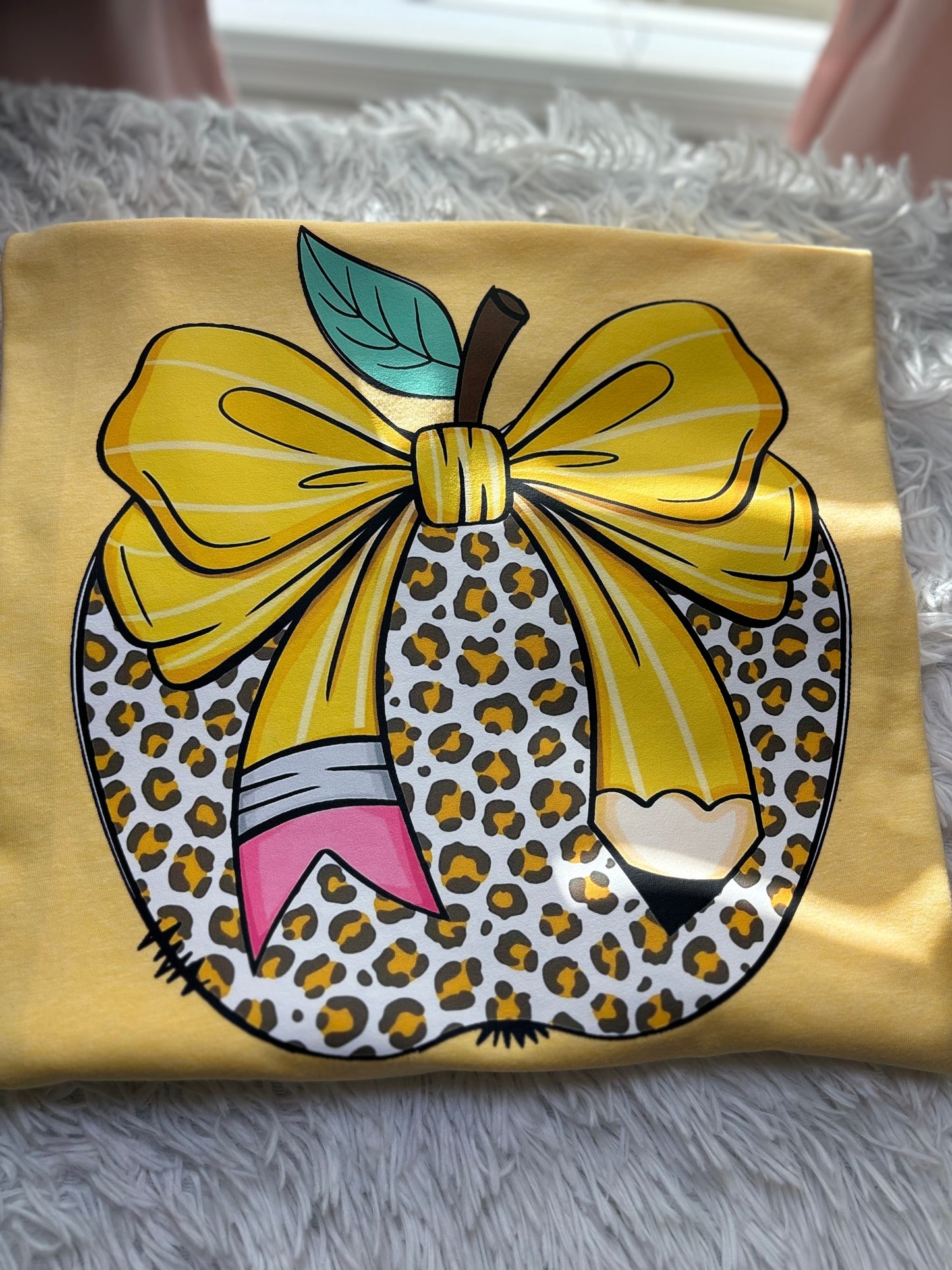 Yellow heat press t-shirt with a large pencil bow design on a leopard apple
