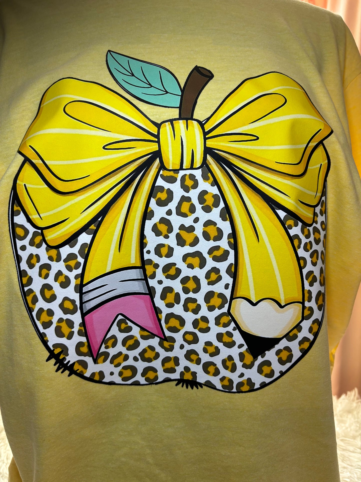 Yellow heat press t-shirt with a large pencil bow design on a leopard apple