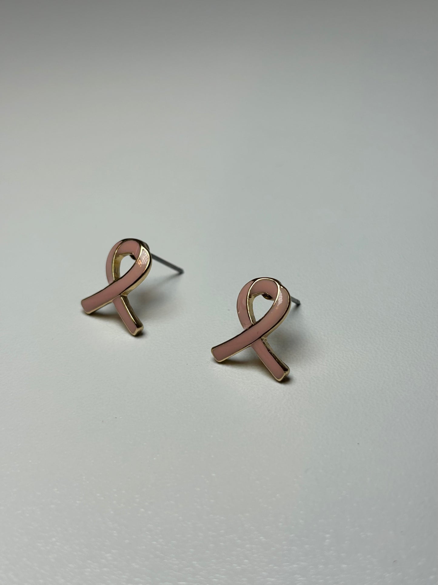 Pink ribbon earrings on a gold background