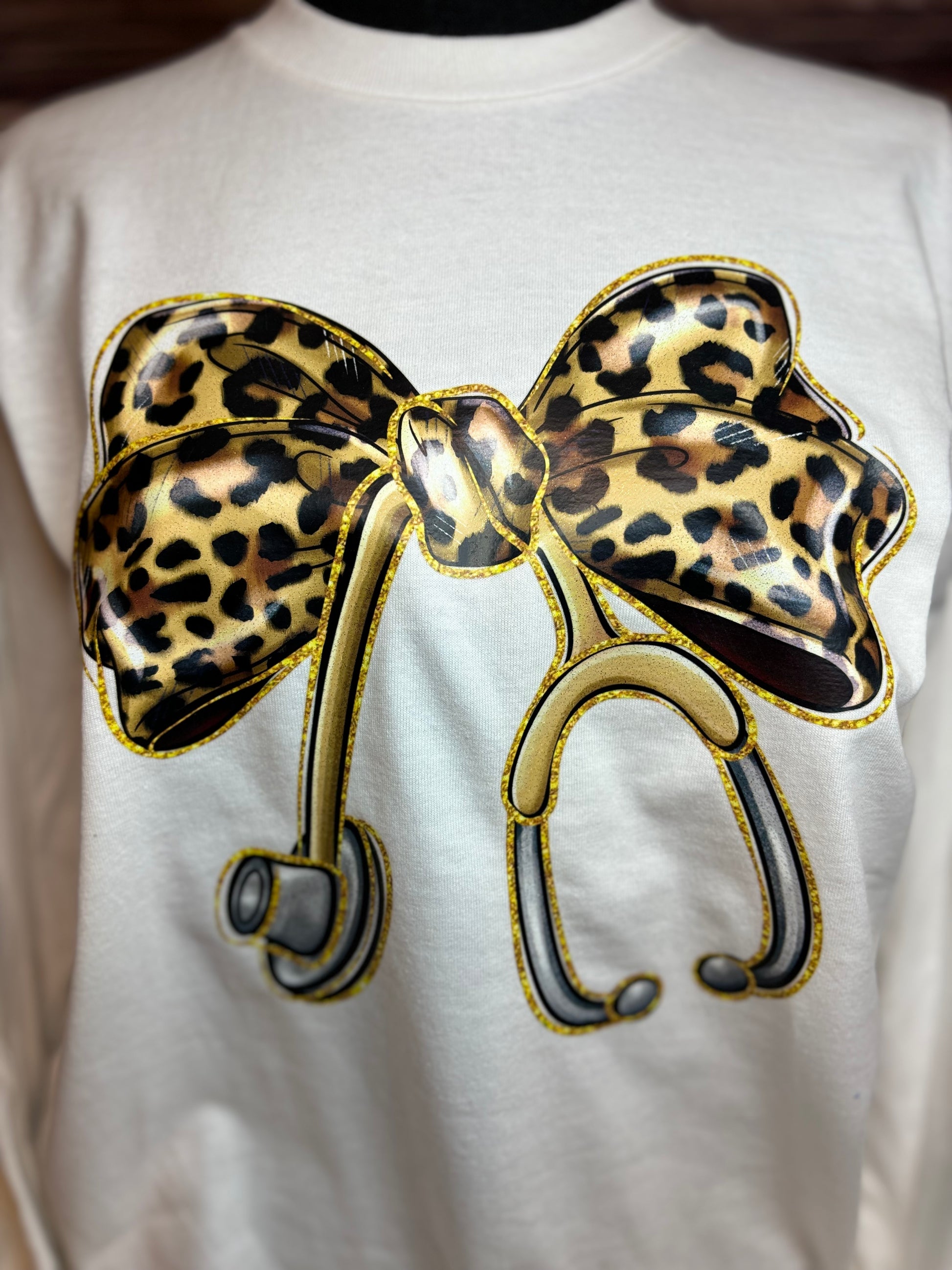 White long sleeve heat pressed t-shirt with a large leopard print bow nurse stethoscope design