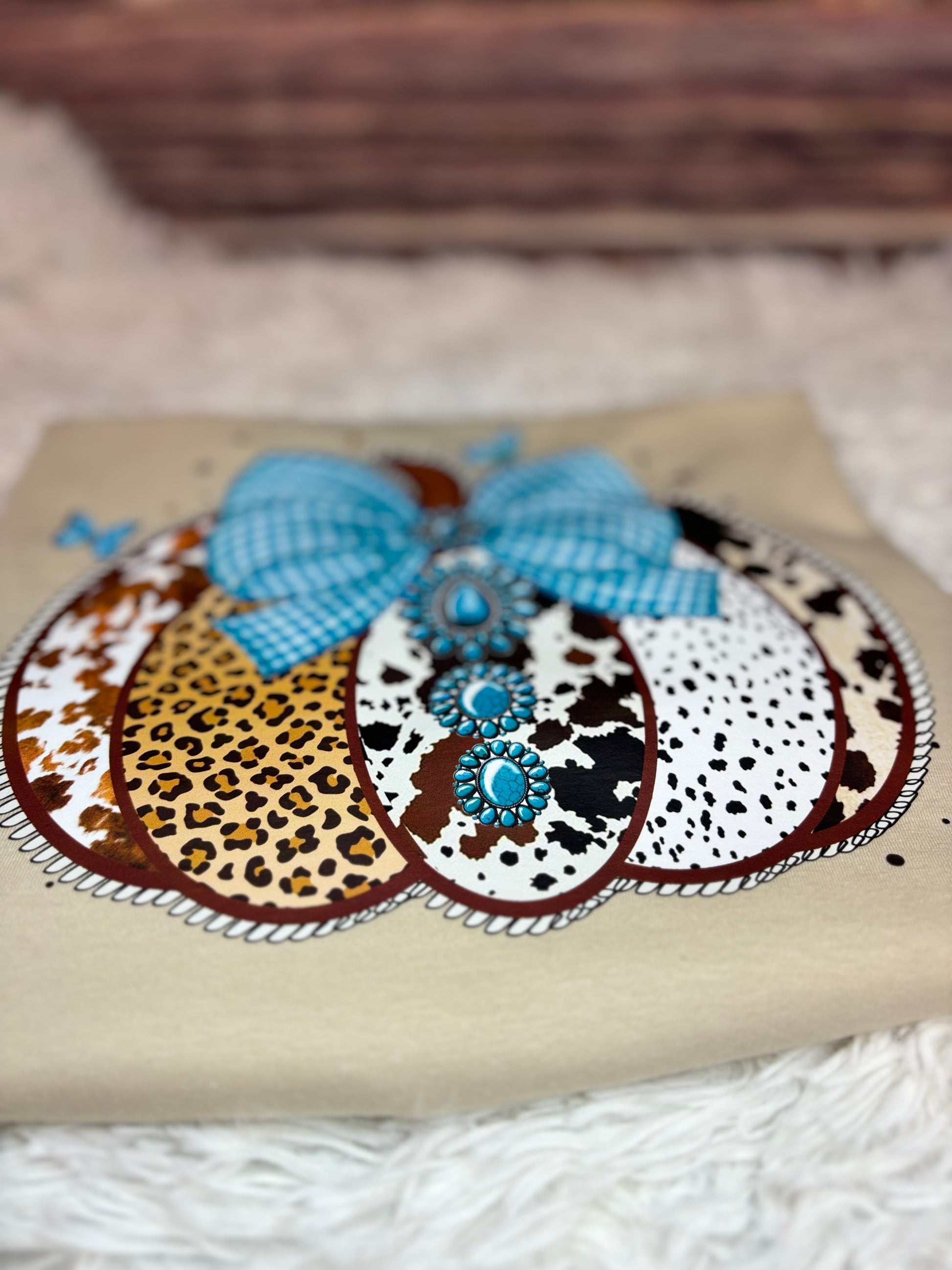 Decorative heat press t-shirt with a western pumpkin that has blue checkered bow, leopard print, and polka dot patterns.