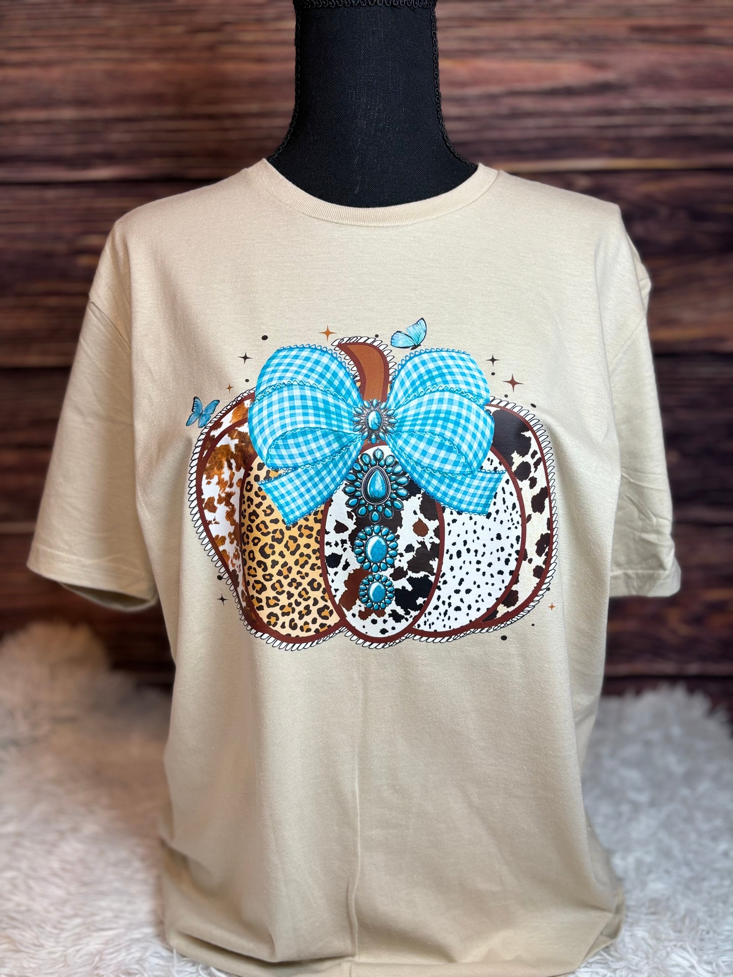 Decorative heat press t-shirt with a western pumpkin that has blue checkered bow, leopard print, and polka dot patterns.