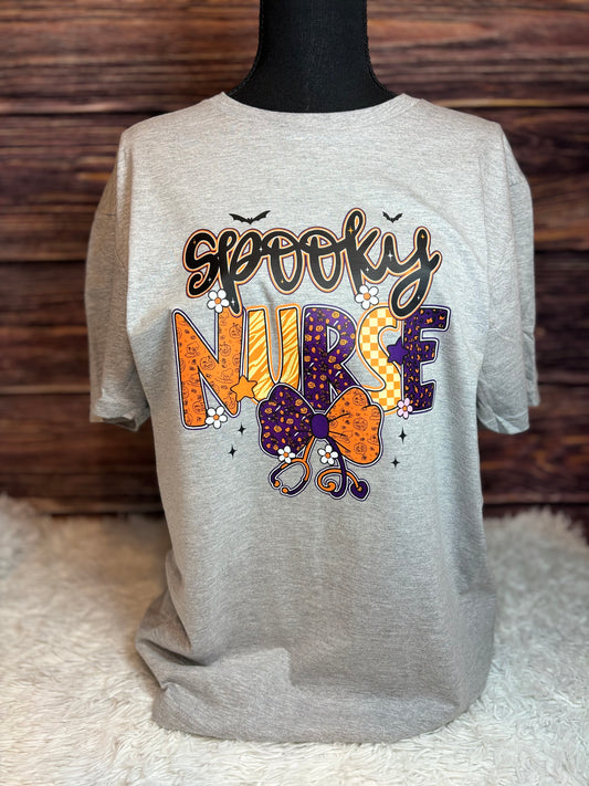 Gray heat press shirt with 'Spooky Nurse' design featuring Halloween elements- bats, stethoscope, flowers, stars