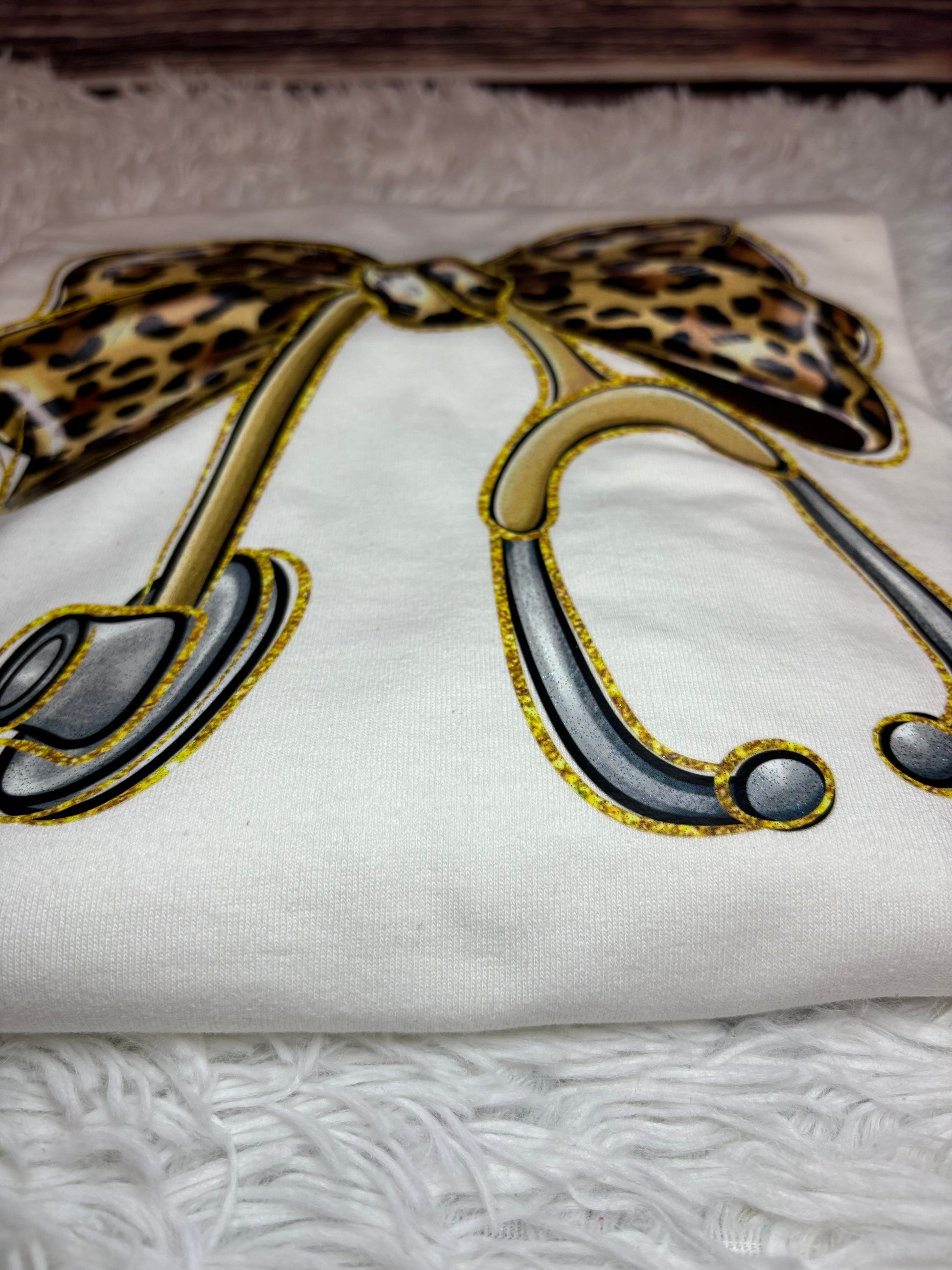 White long sleeve heat pressed t-shirt with a large leopard print bow nurse stethoscope design 